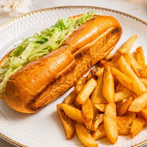 A golden-brown submarine sandwich filled with lettuce and a side of crispy french fries.